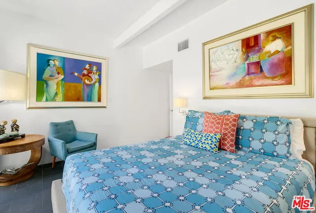 a bedroom with a bed and a lamp on dresser