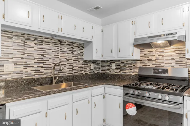 a kitchen with granite countertop a stove sink and cabinets