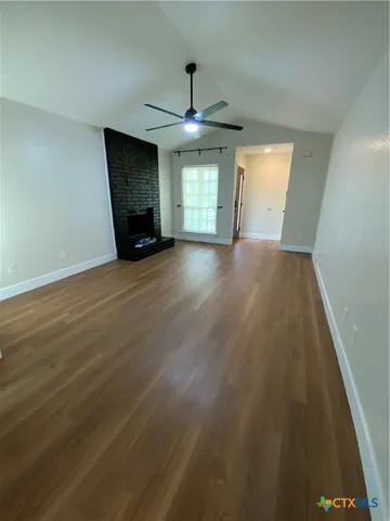 an empty room with wooden floor ceiling fan and windows