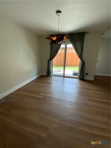 an empty room with wooden floor fan and window