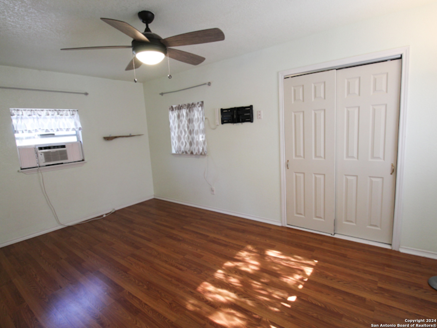 1468 Pebble Beach Road Lakehills, TX 78063 - Photo 16 of 23 a view of an empty room with wooden floor and a window