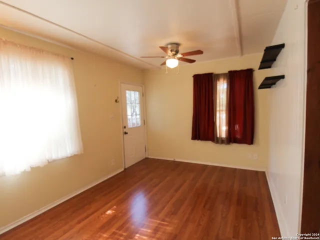a view of empty room with wooden floor and fan