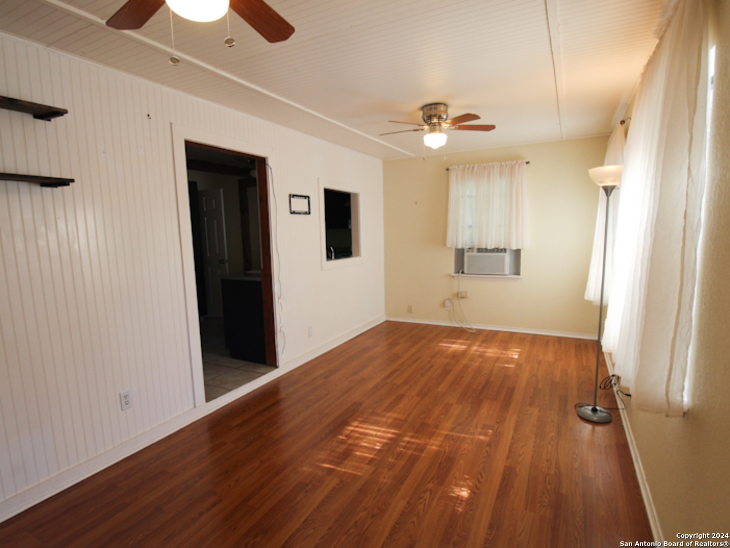 1468 Pebble Beach Road Lakehills, TX 78063 - Photo 8 of 23 a view of an empty room with wooden floor and a ceiling fan
