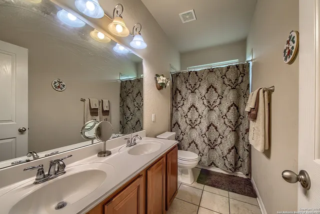 a bathroom with a sink toilet double vanity and shower
