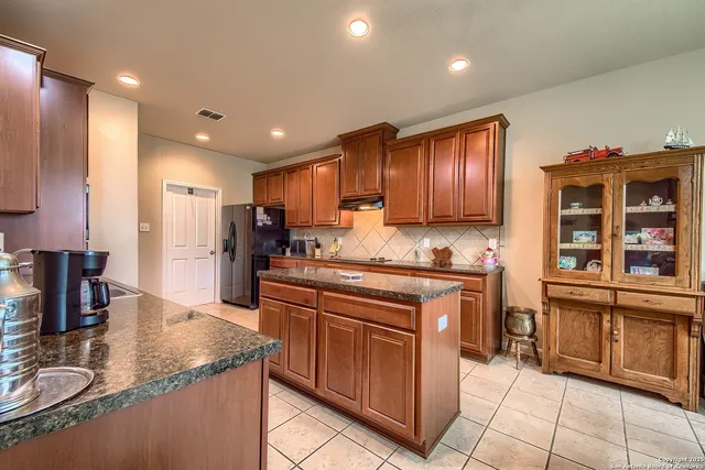 a kitchen with kitchen island granite countertop a stove sink and cabinets