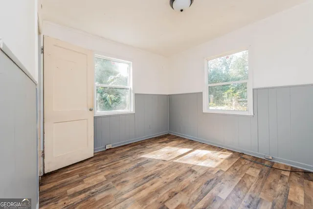 a view of empty room with wooden floor and fan