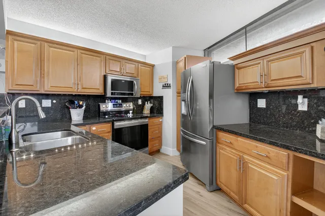 a kitchen with stainless steel appliances granite countertop a refrigerator stove and sink