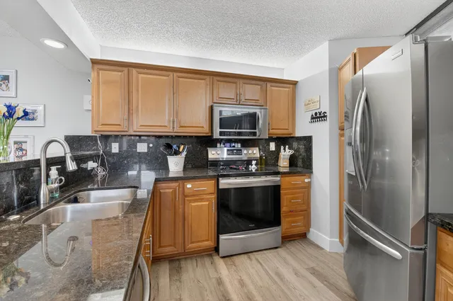 a large kitchen with granite countertop a sink and stainless steel appliances