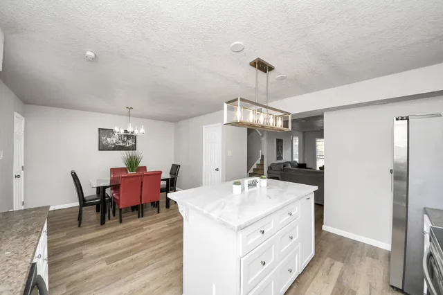 a kitchen with stainless steel appliances kitchen island granite countertop a table chairs and a refrigerator