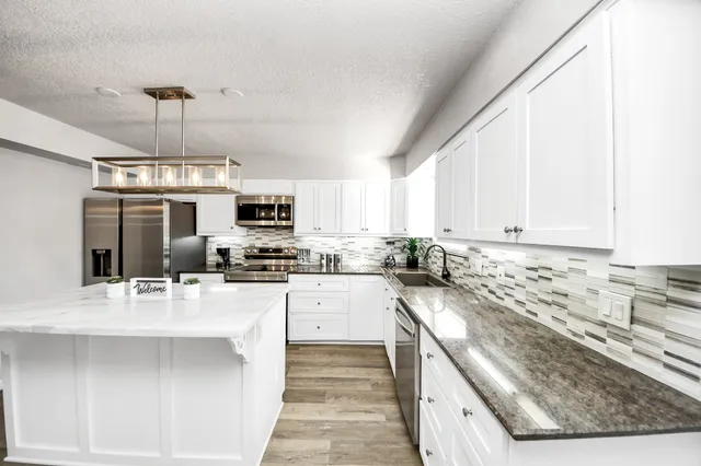 a kitchen with stainless steel appliances granite countertop a sink stove and refrigerator