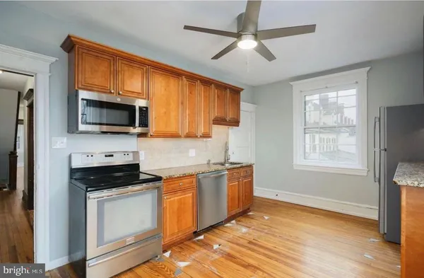 a kitchen with stainless steel appliances granite countertop a stove top oven a sink dishwasher and white cabinets with wooden floor