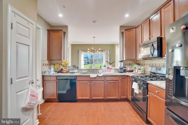 a kitchen with stainless steel appliances granite countertop a stove top oven a sink dishwasher a dining table and chairs with wooden floor