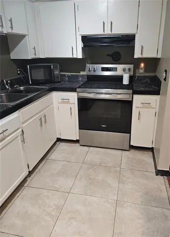 a kitchen with granite countertop a stove a sink and cabinets