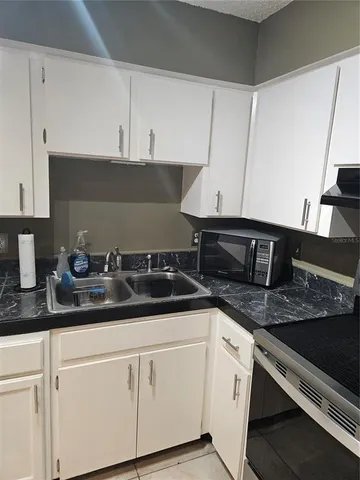 a kitchen with granite countertop white cabinets and a sink