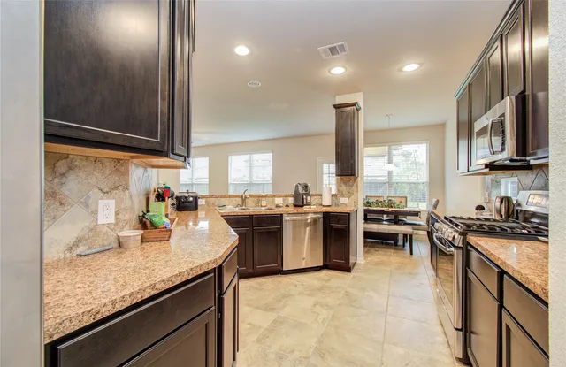 a kitchen with stainless steel appliances granite countertop sink stove top oven and cabinets