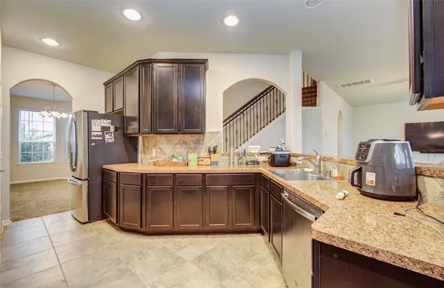 a kitchen with stainless steel appliances granite countertop a sink and a refrigerator