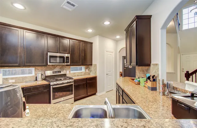 a kitchen with stainless steel appliances kitchen island granite countertop a sink stove and refrigerator