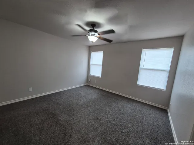 an empty room with a window and a fan