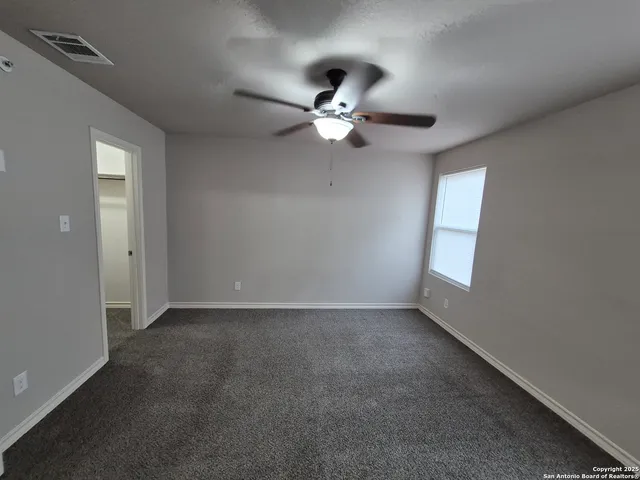 an empty room with a window and a fan
