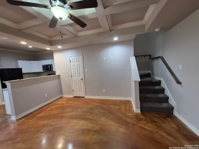 a view of an empty room with wooden floor and a ceiling fan
