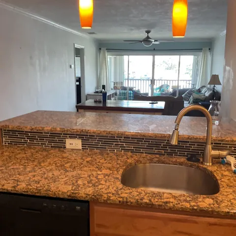 a kitchen with kitchen island granite countertop a sink stainless steel appliances and a window