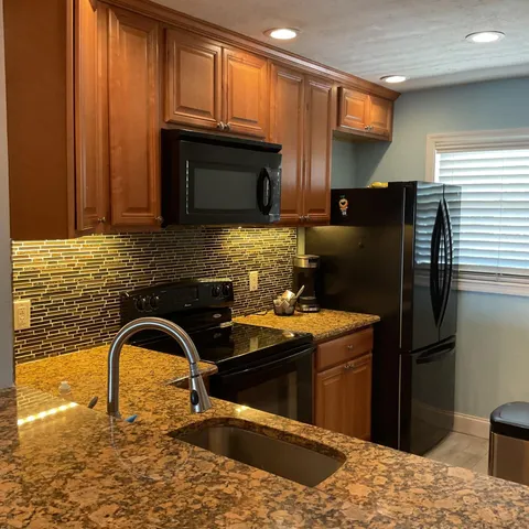 a kitchen with stainless steel appliances granite countertop a refrigerator a stove a sink and a microwave