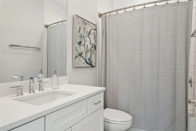 a bathroom with a sink a toilet and shower curtain