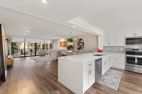 a large white kitchen with cabinets a sink and appliances