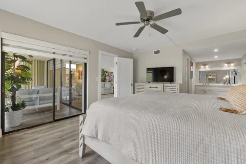 a large white bedroom with a large bed a flat tv screen and chandelier