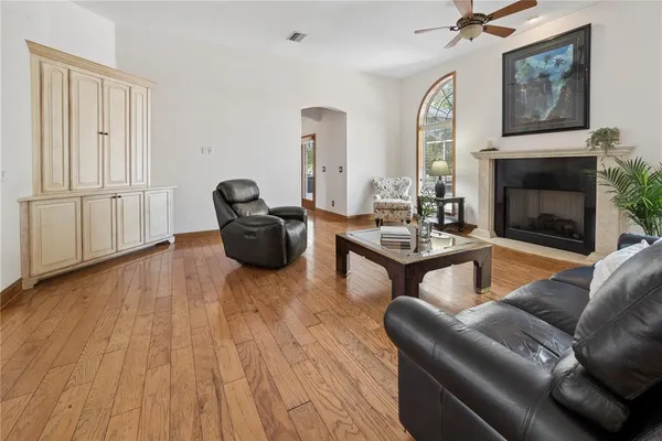 a living room with couches coffee table and a piano table with wooden floor