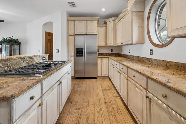 a kitchen with stainless steel appliances granite countertop a stove top oven a sink dishwasher and a refrigerator with wooden floor