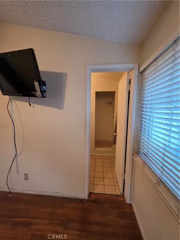 an empty room with wooden floor chandelier fan and windows