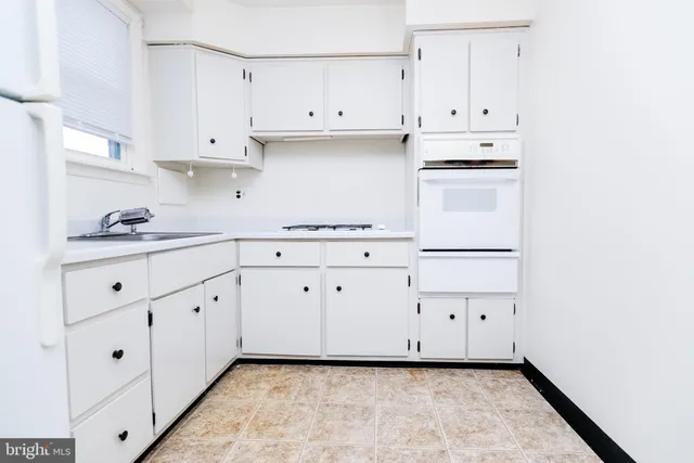 a kitchen with white cabinets and white appliances