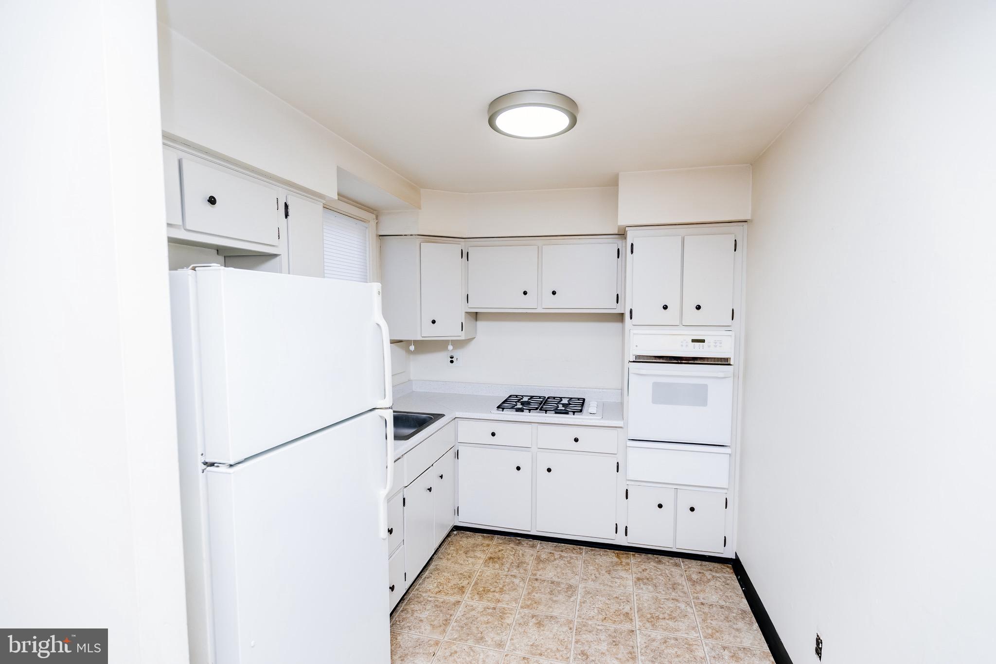 223 Alnus Street Philadelphia, PA 19116 - Photo 4 of 30 a kitchen with white cabinets and white appliances