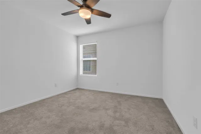 an empty room with a window and a fan