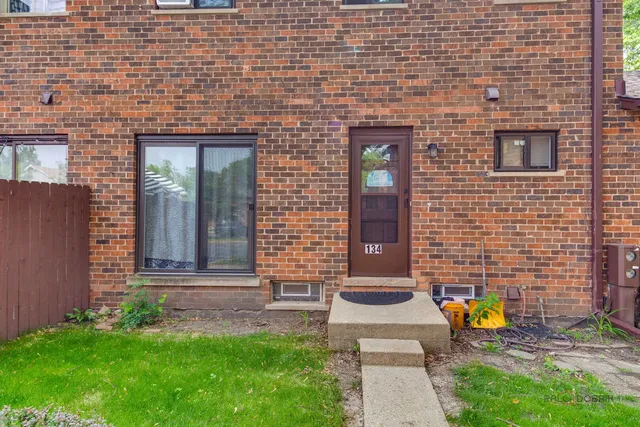 a view of a brick house with a yard and table and chairs