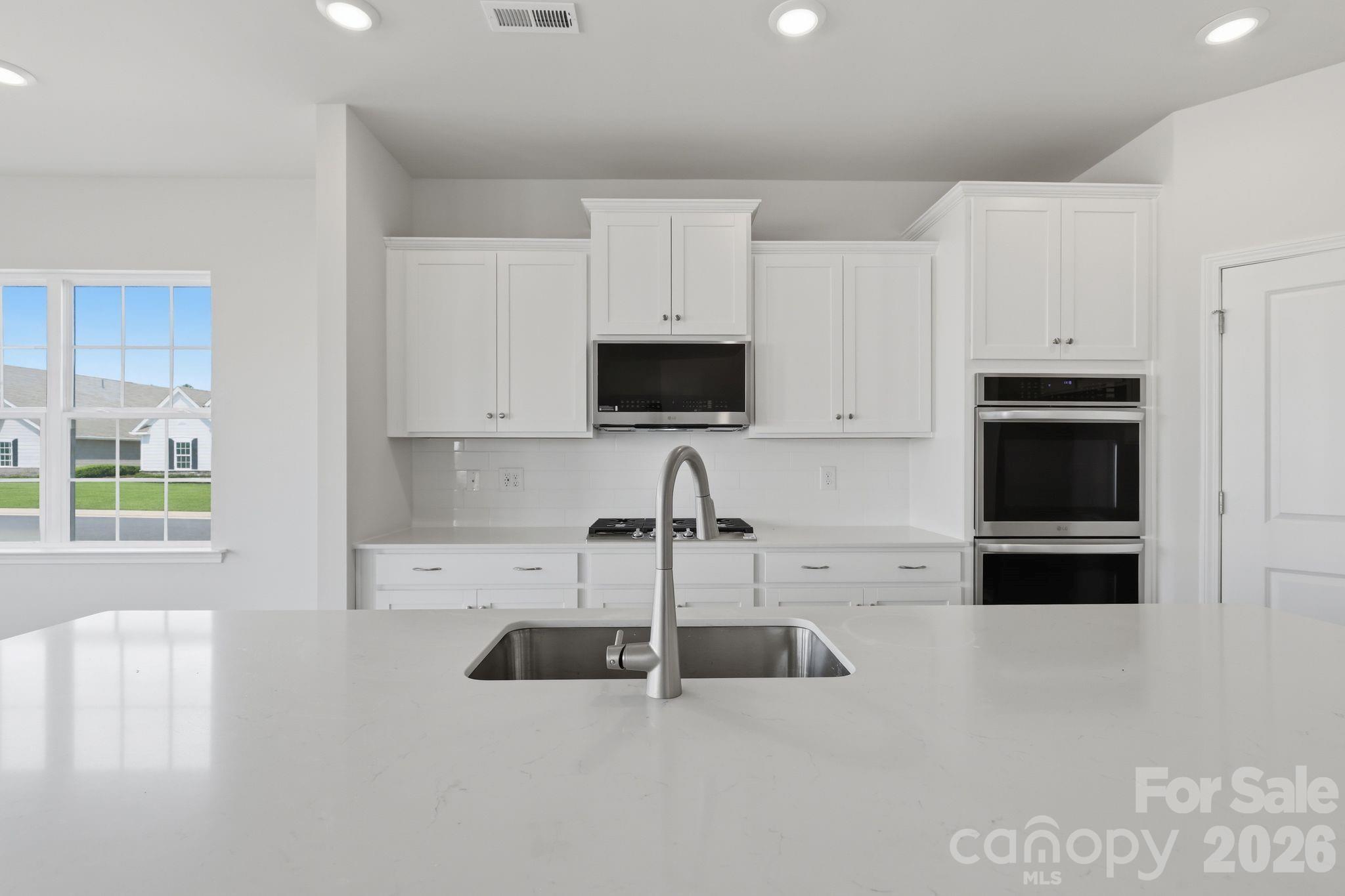5475 Redbud Road, Unit 57 Lancaster, SC 29720 - Photo 16 of 30 a kitchen with stainless steel appliances a stove a sink a microwave and white cabinets