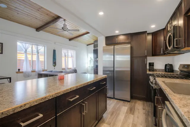 a kitchen with stainless steel appliances granite countertop a table chairs and a refrigerator
