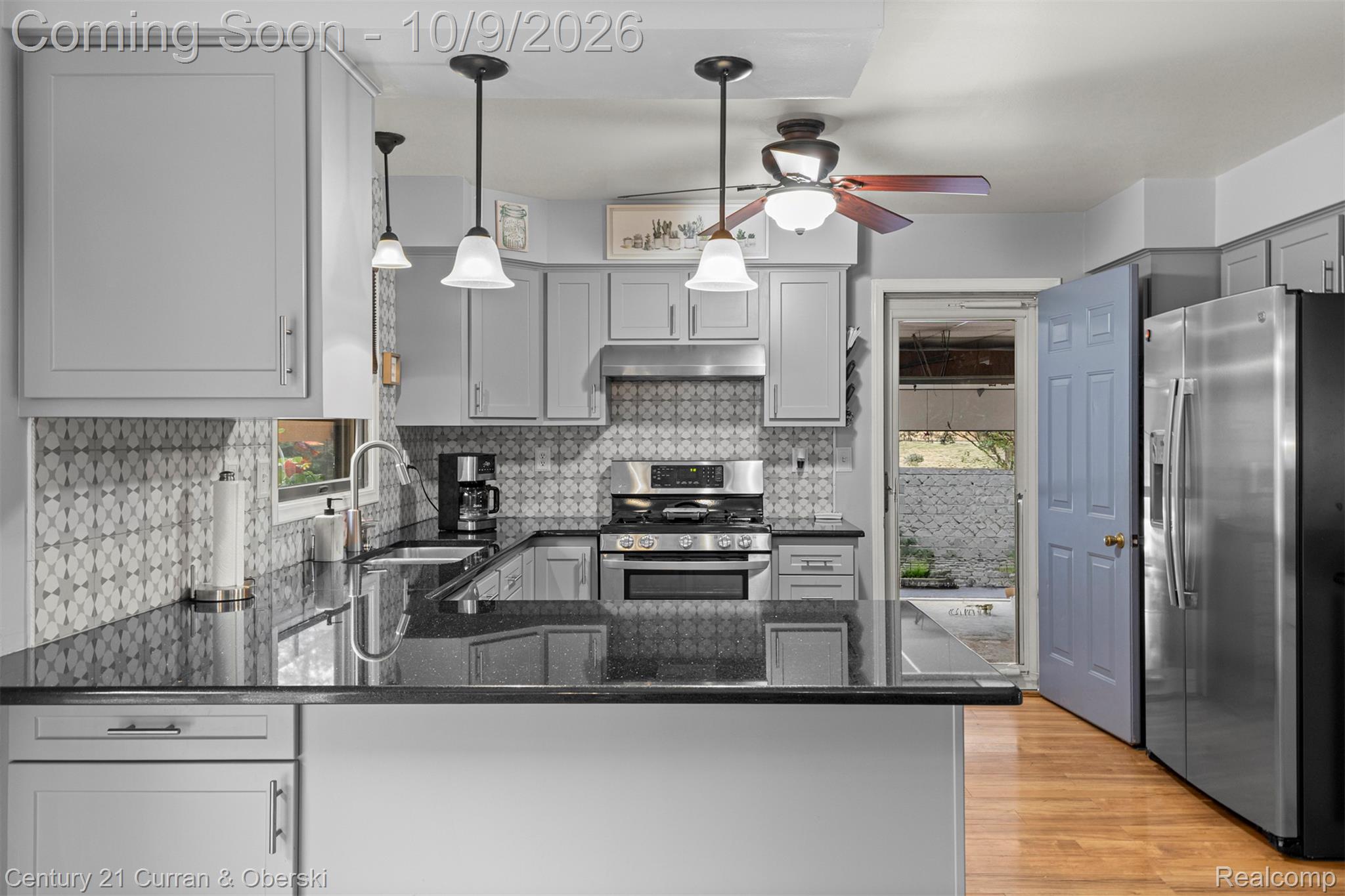 43040 Willis Road Belleville, MI 48111 - Photo 16 of 65 Contemporary kitchen featuring light gray cabinetry, dark countertops, a patterned tile backsplash, stainless steel appliances, and wood-finish flooring