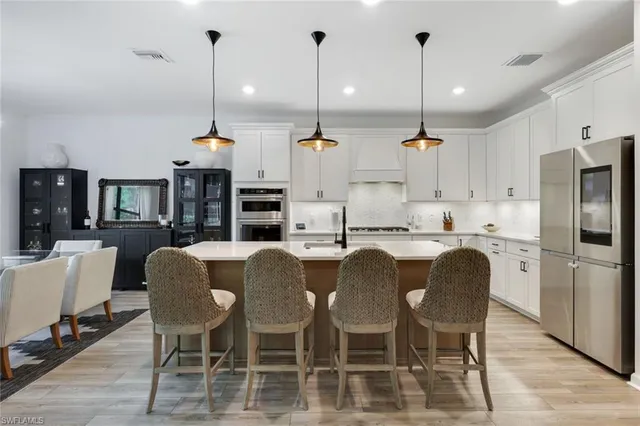 a kitchen with stainless steel appliances kitchen island granite countertop a dining table chairs and white cabinets