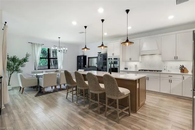 a kitchen with kitchen island granite countertop a table chairs sink and cabinets