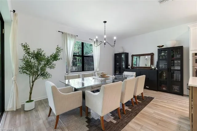 a living room with furniture a chandelier and wooden floor
