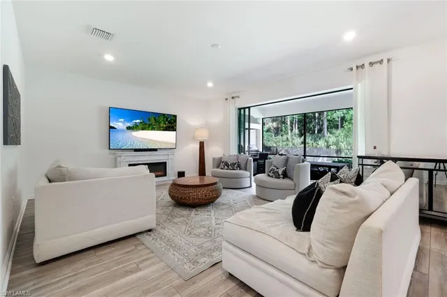 a living room with furniture a flat screen tv and a floor to ceiling window
