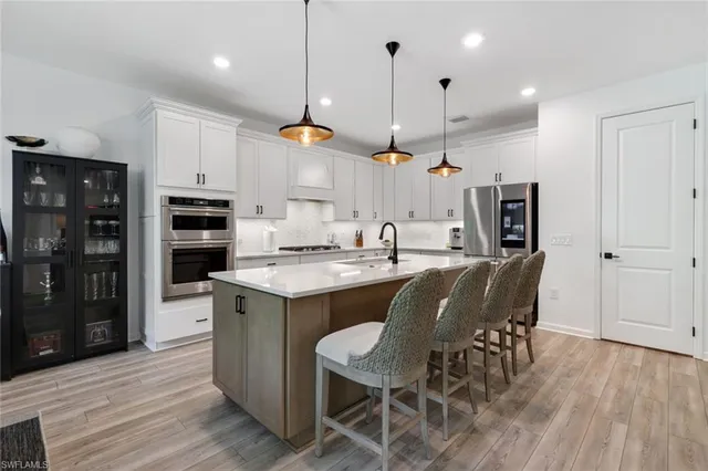 a kitchen with stainless steel appliances kitchen island granite countertop a table chairs and a refrigerator