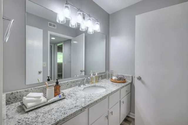 a bathroom with a granite countertop double vanity sink and a mirror