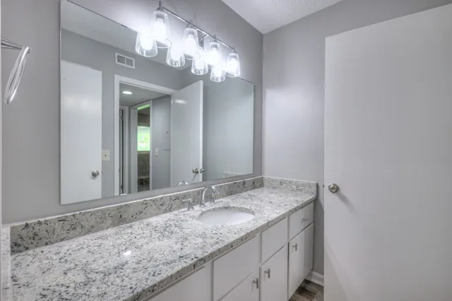 a bathroom with a granite countertop sink and a mirror