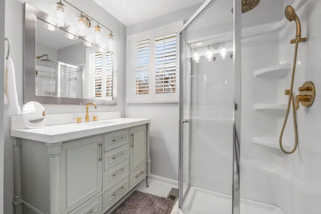 a bathroom with a double vanity sink a window and shower