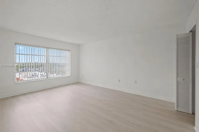a view of an empty room with wooden floor and windows