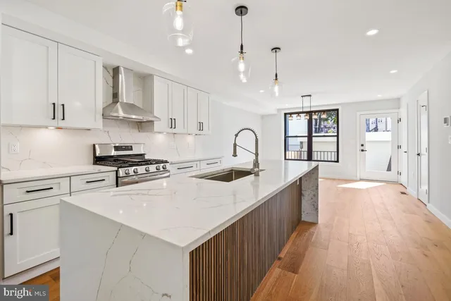 a large kitchen with stainless steel appliances granite countertop a lot of counter space and wooden floors