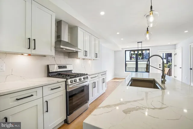 a kitchen with stainless steel appliances granite countertop a stove a sink dishwasher and white cabinets with wooden floor